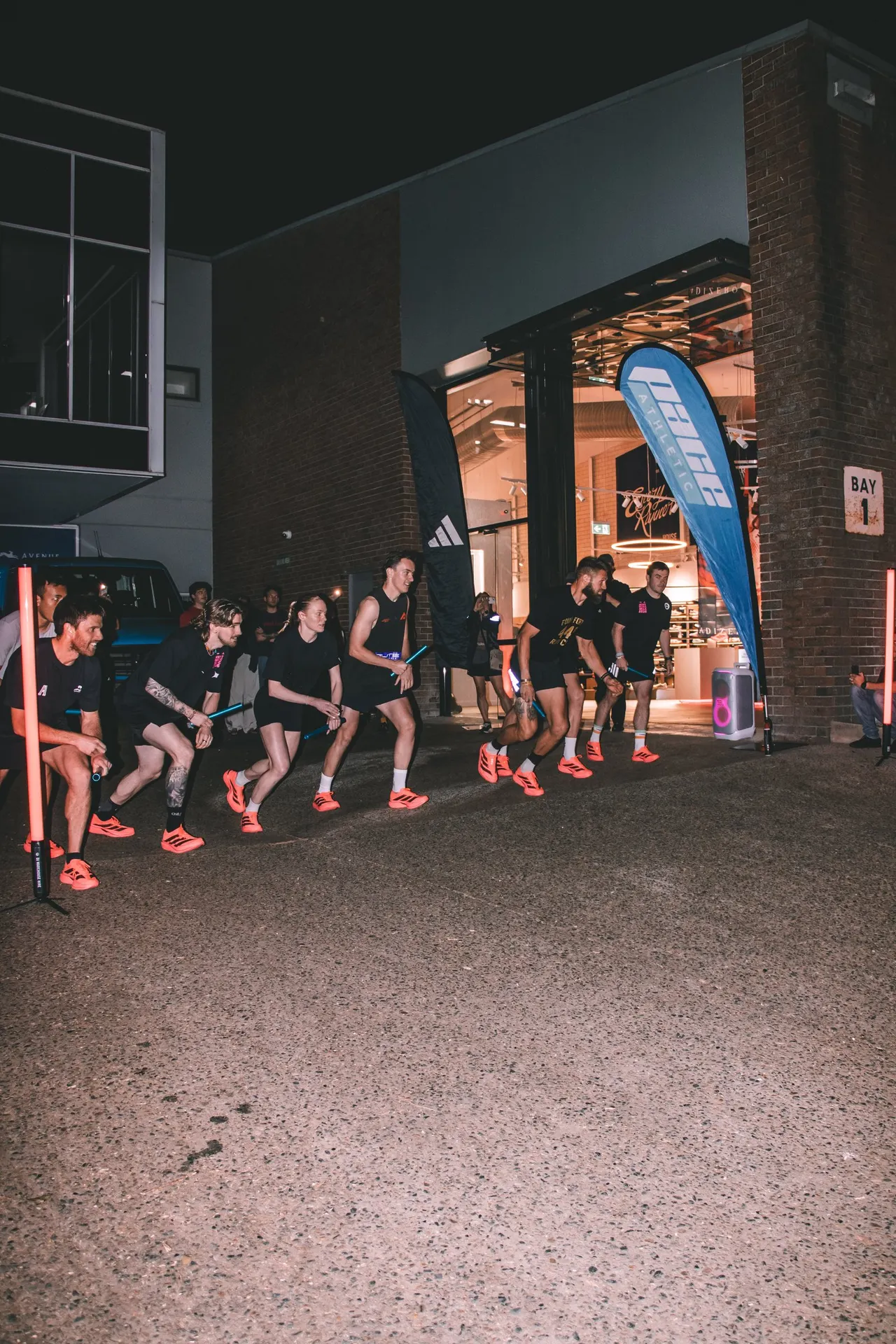 Runners lined up on Mentmore Avenue outside Pace Athletic House of Rec at night