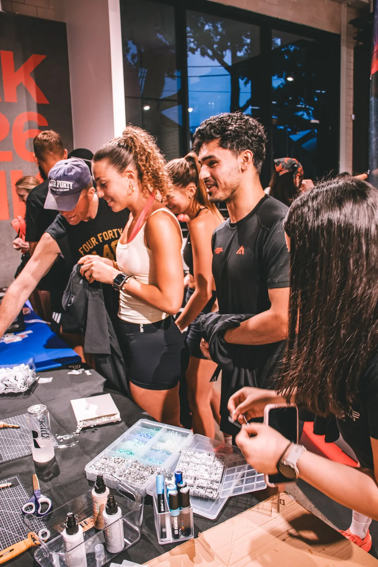Runners from Sydney run clubs customising their club race kit at a table of patches and tools