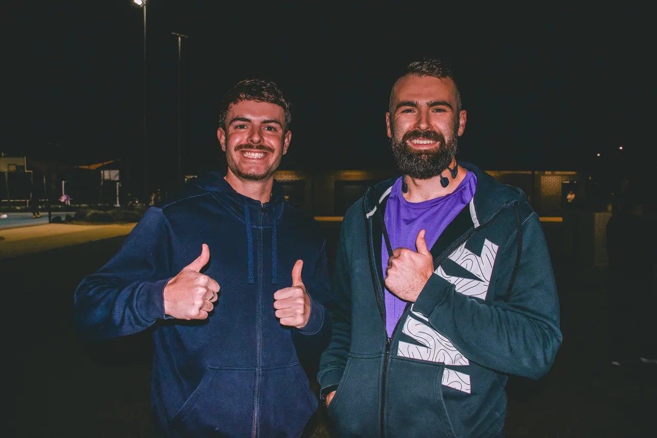Two runners smiling and giving a thumbs up together at a Hills Run Club night run